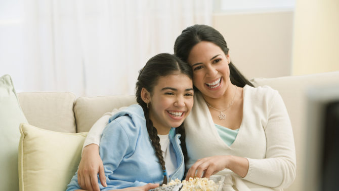 Hispanic mother and daughter watching movie